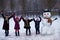 A small cheerful girls near big funny snowman