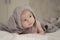 A small child of 1 months in a gray hat with ears looks to the side. Soft light soft focus