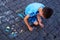 A small child with autism syndrome draws with chalk on the pavement