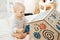 Small child in body plays with a wooden house in a bright room on the bed, developing his motor skills.