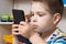 A small child boy 3-4 years old looks into the phone screen. Parental control of content, internet and cartoons in the