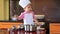 The small child in chef suit helps her mother cook in the kitchen
