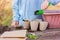 A small child with a children`s shovel pours soil into pots for planting seedlings