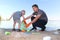 A small child collects trash on the beach. His dad points his finger where to throw garbage. Parents teach children cleanliness.