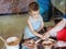 Small child with craftsperson make clay bowl.