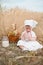 A small child drinks cows milk from a glass in a field of wheat. World Milk Day