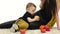 Small child eats an apple, next to her mother. White background