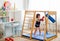 A small child is engaged in boxing on a wooden home sports complex. Girl in boxing gloves hits the pear.