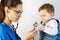 A small child on examination at the doctor looks at the stethoscope and pulls his hand to him