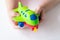 A small child holds a green toy airplane. The concept of imagination, children`s games, travel, leisure, tourism