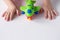 A small child holds a green toy airplane. The concept of imagination, children`s games, travel, leisure, tourism