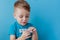 A small child holds in his palm a handful of pills on blue background