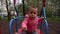 A small child infant swings on a swing and tries to reach for the camera with his finger. Girl dressed in a pink sweater and white