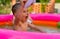 A small child in an inflatable kids round pool in sunny summer weather