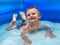 A small child in an inflatable kids round pool in sunny summer weather