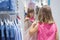 A small child measures her skirt in front of a mirror in a store. Shopping, shopping