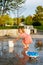 Small child at playground in park playing with water and toys. Little girl at splash pad in summer