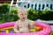 A small child plays in an inflatable pool, learns to swim, playing with colorful inflatable toys