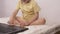 A small child presses a finger on the button on the laptop keyboard, close-up, baby and computer.