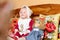 A small child in a shawl sitting on a sofa with embroidered pillows