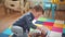 A small child sits on the floor and plays with a variety of animals