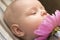 A small child smells a pink peony flower, close-up