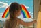 A small child stands on the windowsill and draws a rainbow on the window glass. multi-colored rainbow. symbol of happiness. select