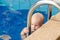 Small child tries to climb out of the pool. The girl holds hands for a side and handrails.