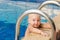 Small child tries to climb out of the pool. The girl holds hands for a side and handrails.