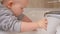 A small child washes his hands with his mother in bathroom above the sink. Baby bathes. A mother helps her child wash