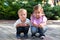 Small children, girl and boy, brother and sister, squat and carefully look at the camera, waiting for the bird to fly out of the