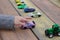 a small children& x27;s hand points to one toy car among a multitude of cars on a wooden red-yellow table