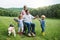 Small children with senior grandparents and dog on a walk on meadow in nature.