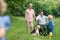 Small children with senior grandparents and dog on a walk on meadow in nature.