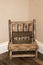 Small childs rustic wooden chair sitting in the corner of a room with wooden sign that says HAPPY on it