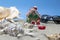 A small Christmas toy in the shape of a gingerbread house stands on a sandy beach next to beautiful shells. Merry Christmas by the