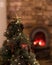 A small Christmas tree with a fireplace burning away in the background