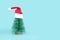 Small Christmas tree in red Santa Hats. Decorating of Artificial Fir tree. Beautiful imitation of a mini Christmas tree