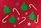 Small Christmas trees, snowflakes and candies on a red background. Christmas background.