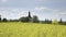 Small church, baroque chapel with belfry at field with oilseed rape