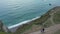 Small Church on Hill, Aerial forward tilting down revealing Cliffs and Ocean with Overcast Sky