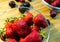 Small clear glass bowl of red organic strawberries standing on a chopping board