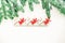 Small colored figures of angels with Christmas tree branches on a light background with shiny snowflakes. Snowfall. Copy space