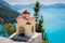 Small colorful Hellenic shrine Proskinitari near edge cliff. Amazing sea view to coastline in the background