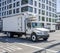Small compact rig semi truck with refrigerator box trailer transporting goods on the street of urban city with multilevel