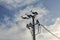 Small concrete pillar with power lines, sky with clouds in background.