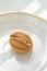 Small cookie walnut on a white saucer and a sunny table