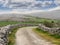 Small country road in Ireland, Stone fences, Cattle in the fields, Cloudy sky. Mountains in the background. Burren region