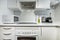 small covered kitchen with white wooden furniture, white wooden countertop,