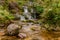 Small cozy waterfall in forest on sunny day